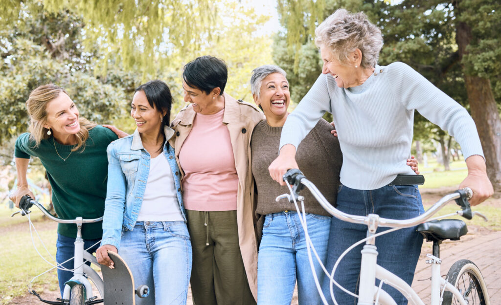 Happy senior people, friends and laughing in joyful happiness enjoying fun time together at the park. Group of elderly women bonding and sharing joke, laugh or walking and cycling in the outdoors