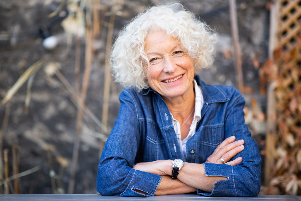 Portrait happy older woman with arms crossed outside