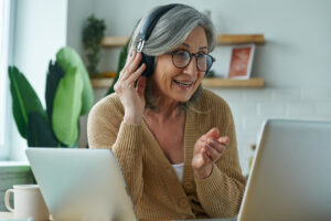 Cheerful senior woman looking at laptop and gesturing while working from home